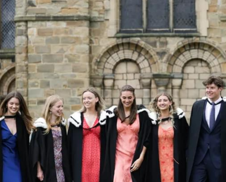 A large group of students in graduation gowns outside Durham Cathedral