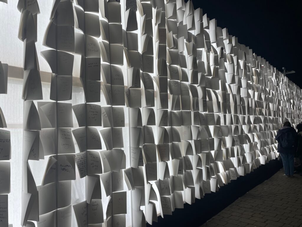 A light art exhibit consisting of a wall of suspended paper booklets lit from the back