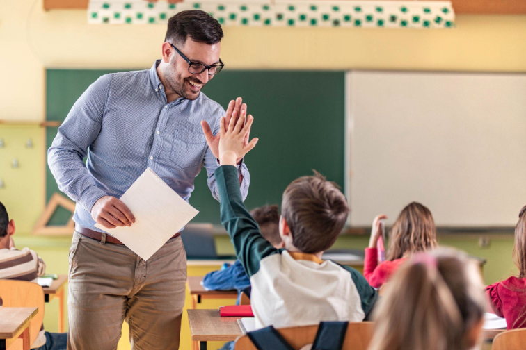A teacher high-fiving a pupil in a classroom