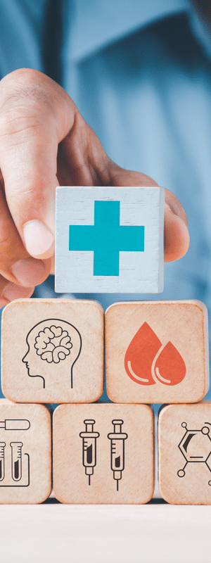 A hand with a stack of wooden blocks with health images