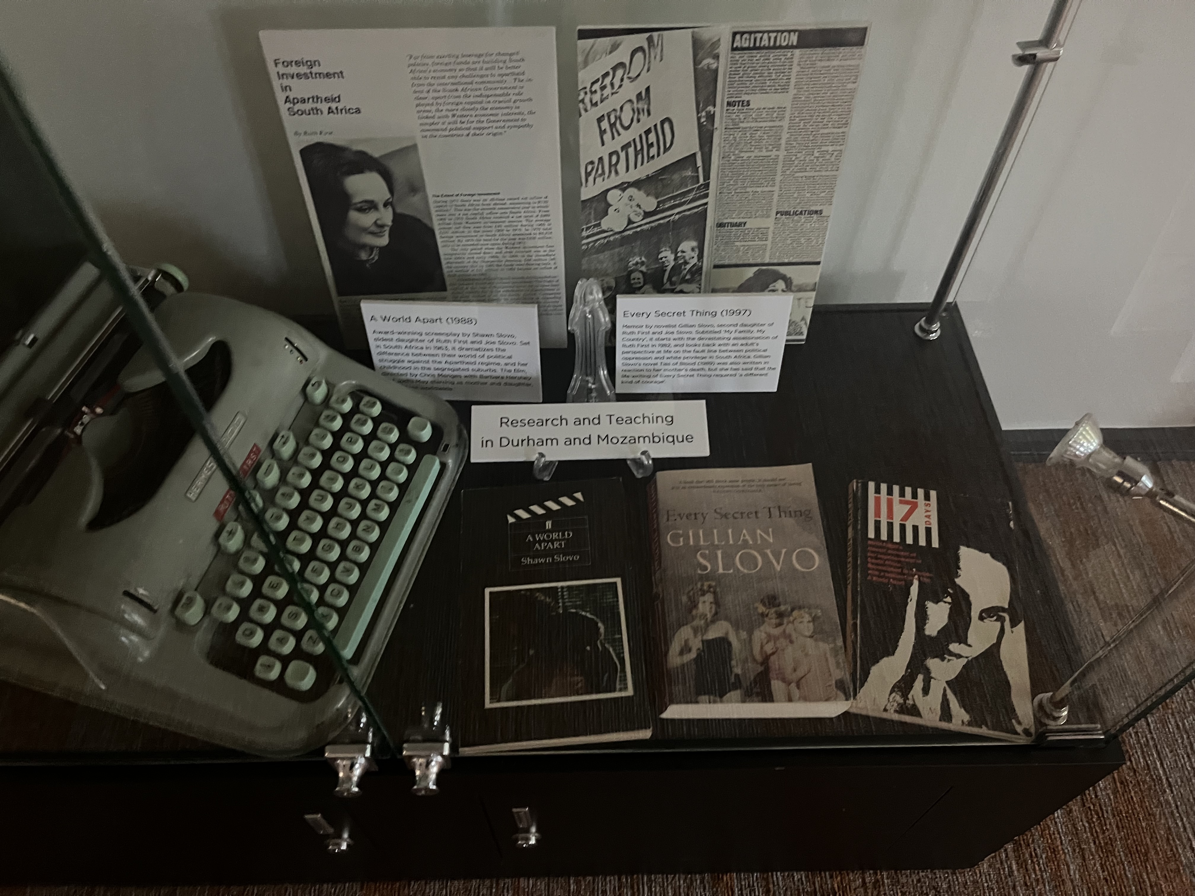 A glass cabinet with books, typewriter and news clips about Ruth First