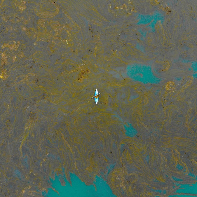 Aerial shot of a kayak on a polluted body of water.