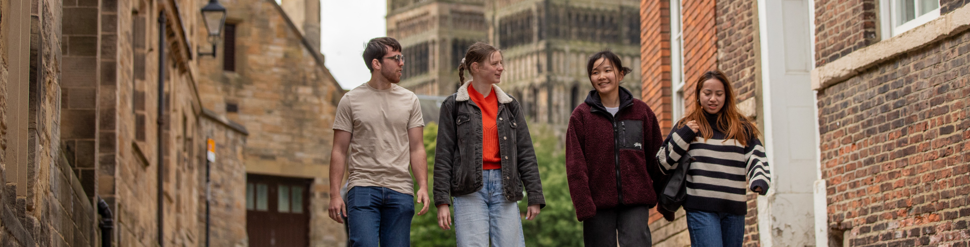 Four students walking with cathedral in the background.
