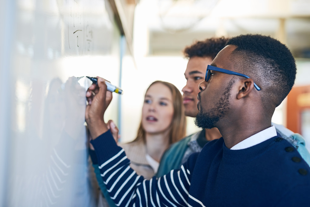 Male student writing on white board