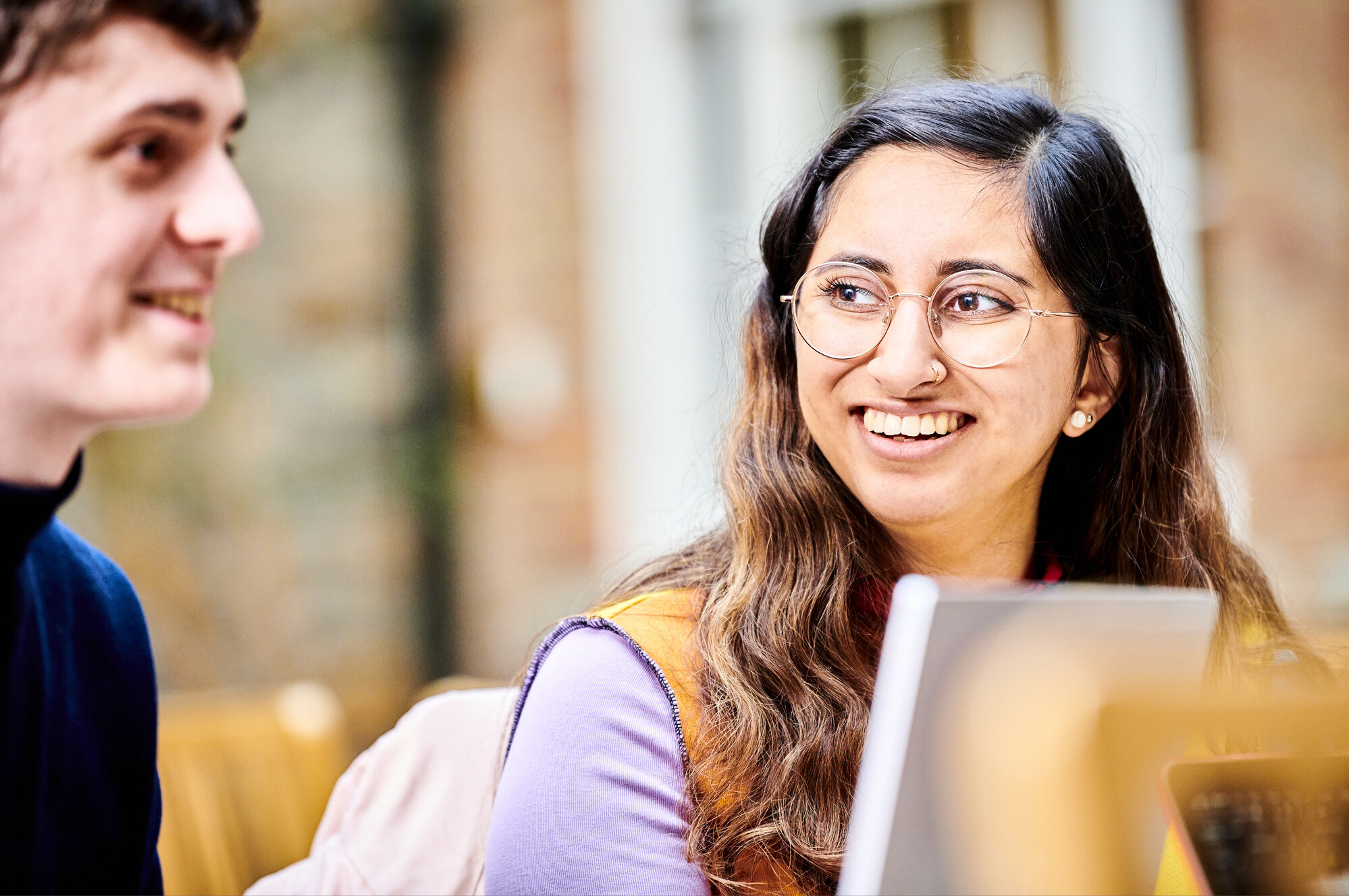 Female student smiling at the person next to her - laptops in the foreground