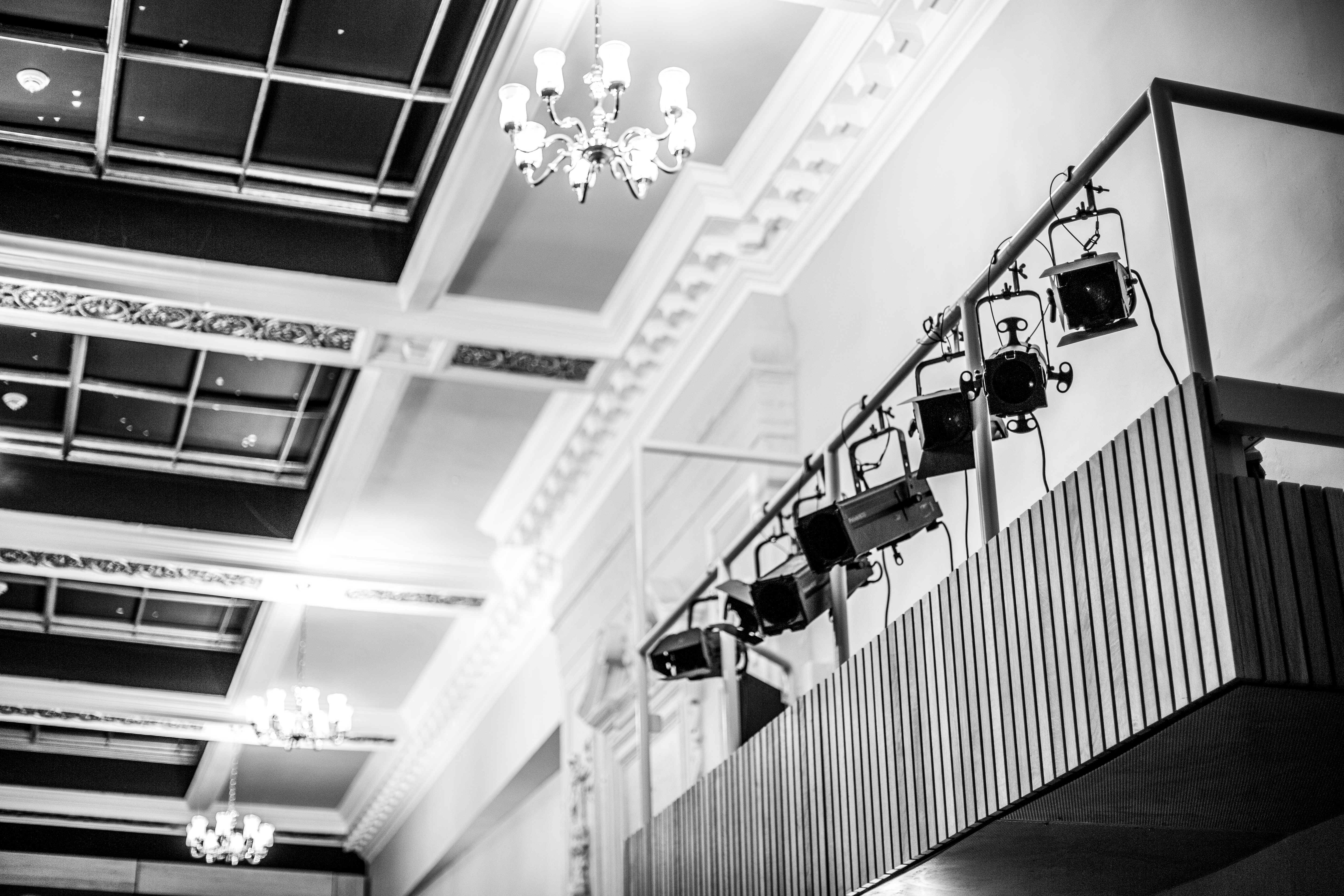 A theatre's ceiling and a bank of stage lights viewed from below in black and white