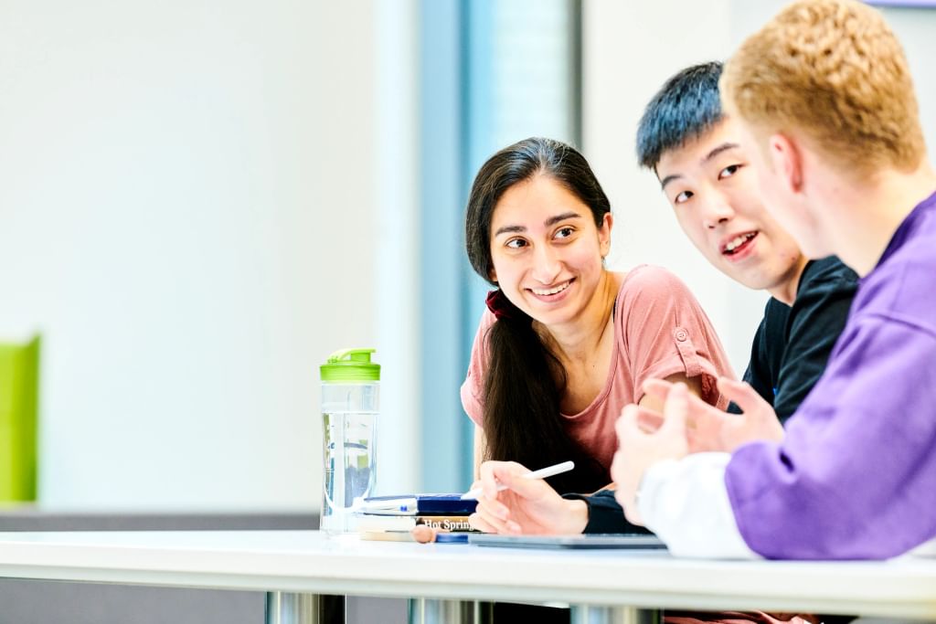 Group of students sitting at a table and talking.