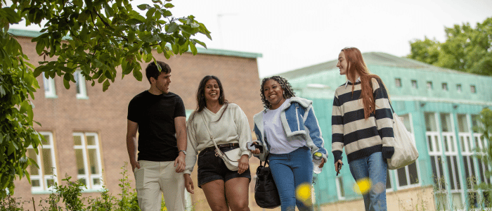 Four students walking and chatting on campus