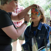 A child having her face painted in the Botanic Garden