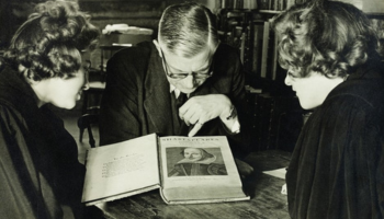 Black and white photograph of three people study a copy of Shakespeare’s first folio at Palace Green Library.